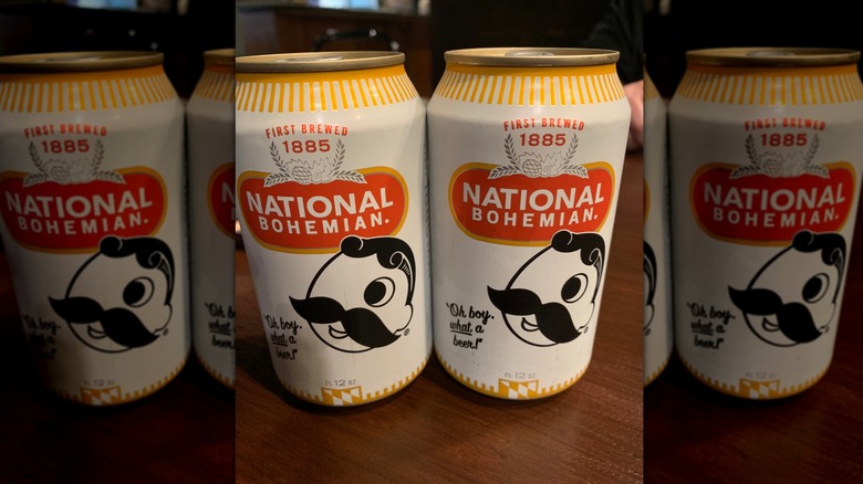 Two cans of National Bohemian beer on a wooden table