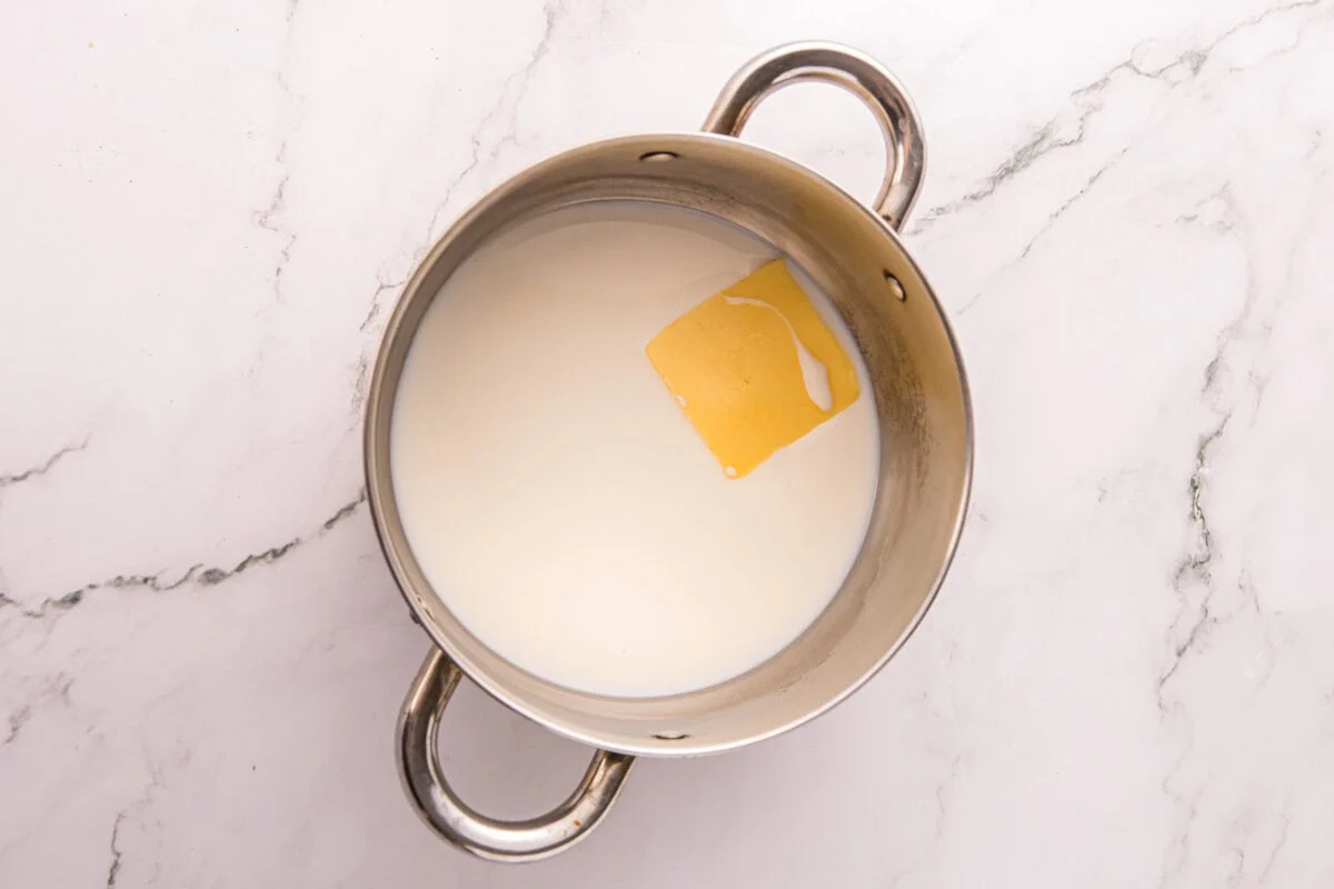 Milk and a pat of butter in a saucepan, the first step in making the cheese sauce.