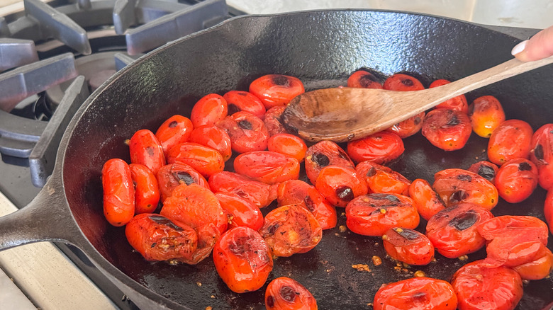 wooden spoon pressing on tomato