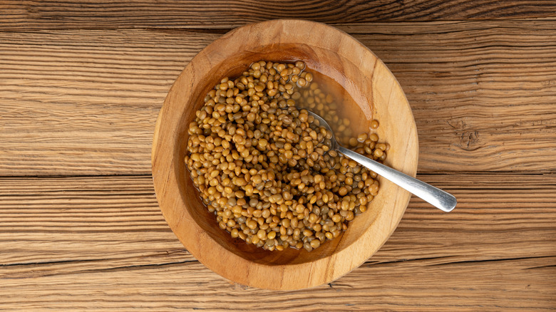 Cooked brown lentils in wooden bowl with spoon