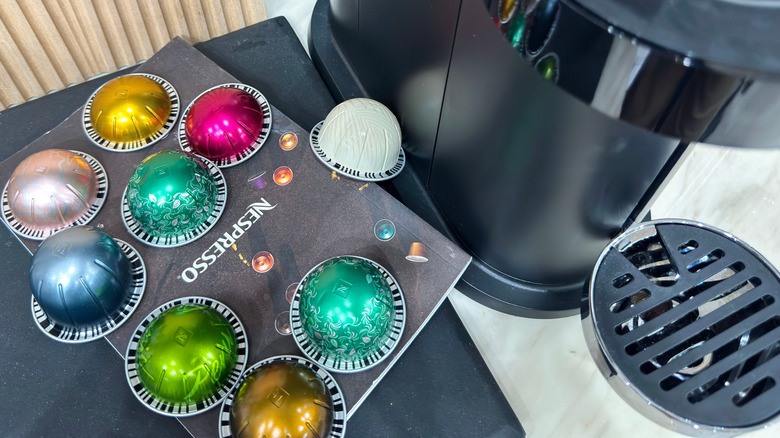 Different colored Nespresso Vertuo pods next to a Nespresso machine.