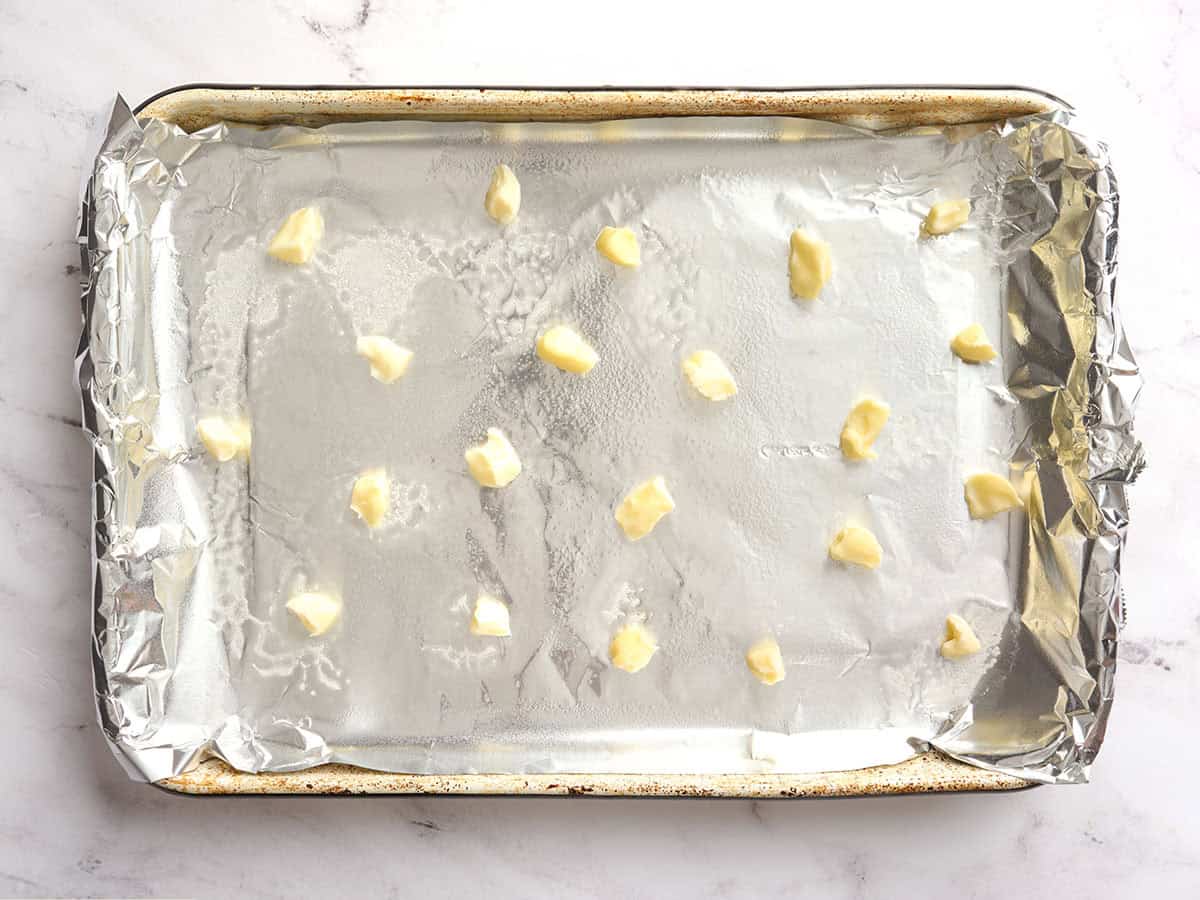 Foil lined baking sheet dotted with pieces of butter before the chicken wings are added.