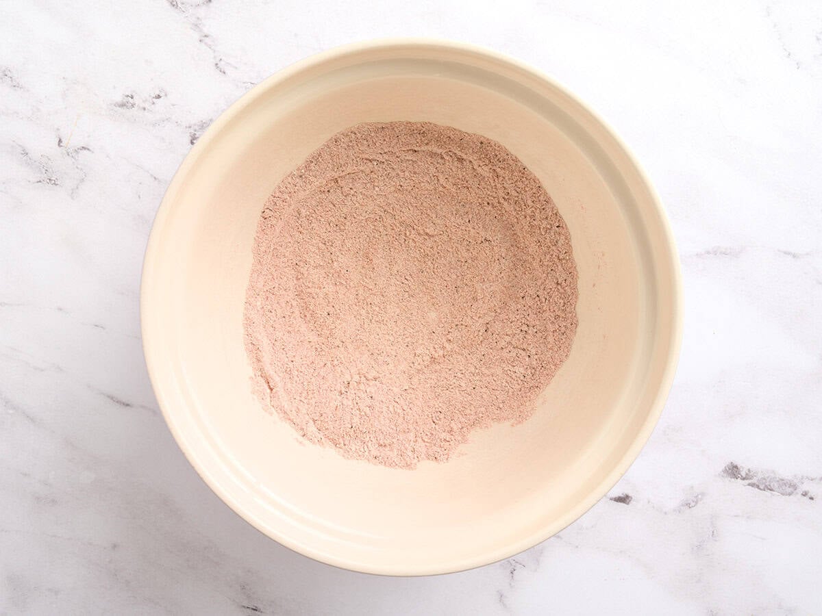 Bowl of dry flour and paprika seasoning mixed together for coating chicken wings.