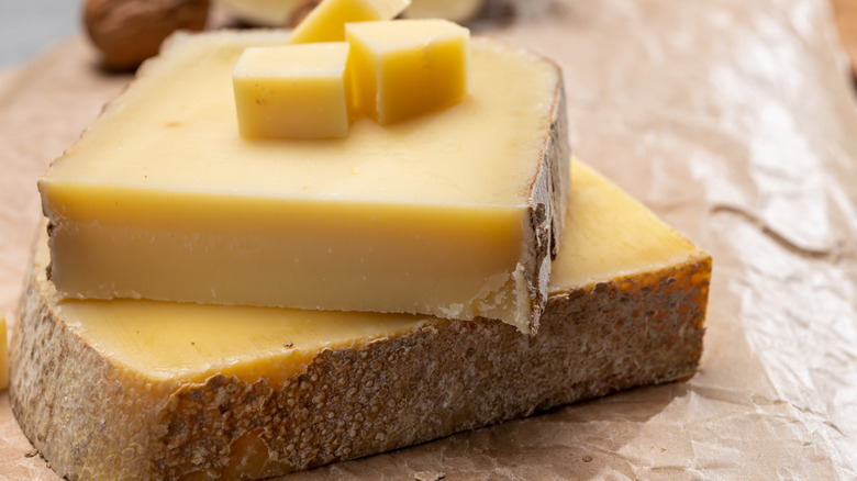 Comté cheese is sliced into blocks and set on parchment paper.