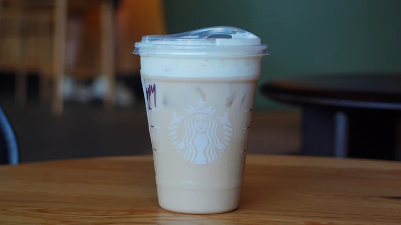 Starbucks Iced Banana Bread Chai on wooden table served in a plastic Starbucks cup