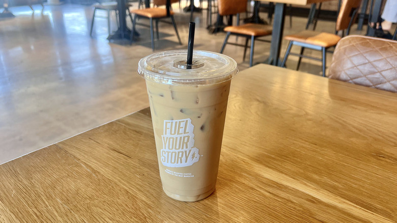 Black Rock Iced Latte with Banana served in a plastic cup with a straw on a wooden table