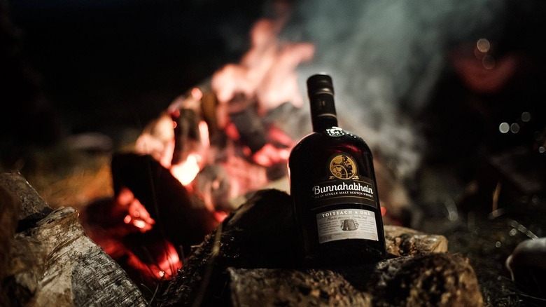 A bottle of Bunnahabhain Toiteach A Dhà paced in front of a blurred smoky fire background