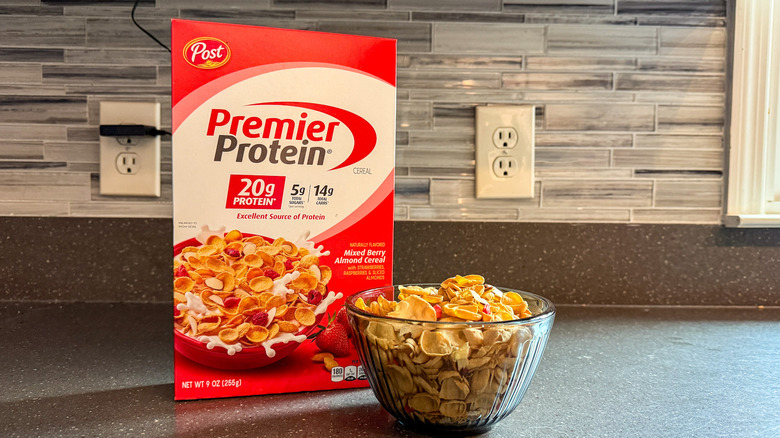 A bowl of Post's Premier Protein Mixed Berry Almond Cereal with a box of the food beside it on a marble counter