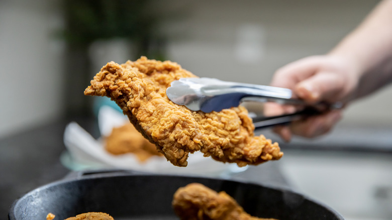 cook removing friend chicken piece
