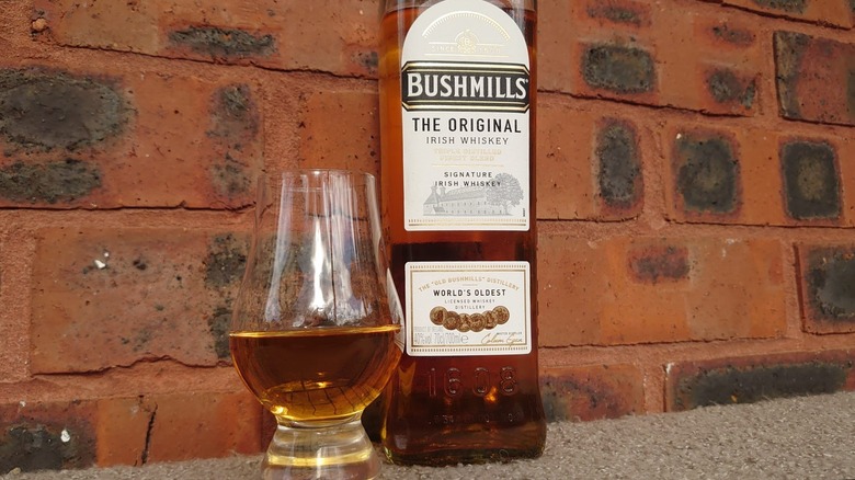 A bottle of Bushmills Original next to a filled Glencairn glass