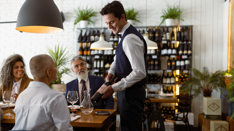 Group of diners consulting their server about wine options
