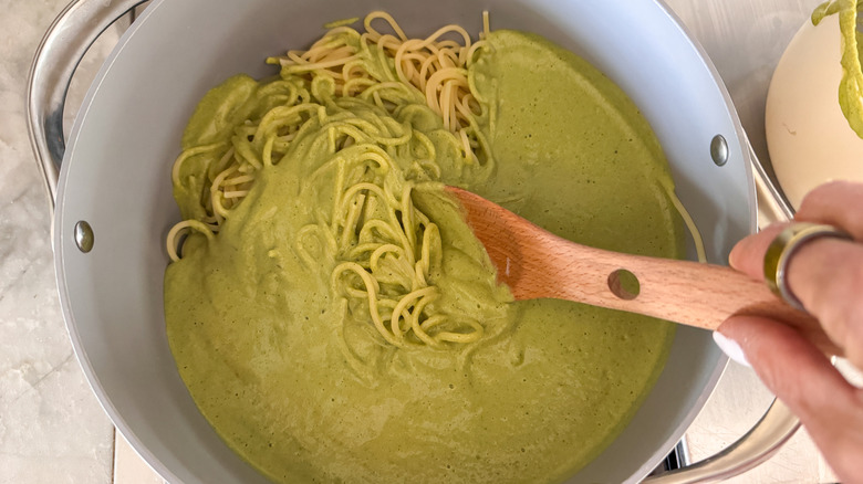 hand mixing pasta and sauce