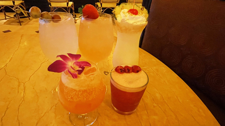 Five fruity cocktails from The Cheesecake Factory sit on a marble table in a booth.