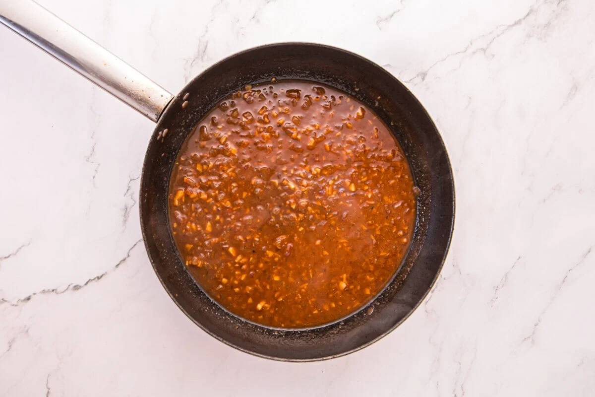 Browned tomato paste and wine simmering into a deep red sauce in the skillet.