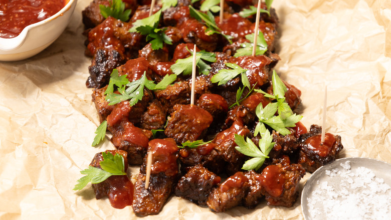 Close up on steak bites on tray with parchment paper next to sauce and salt