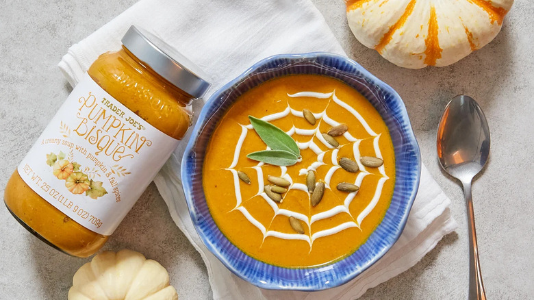 A bowl of pumpkin bisque garnished with pepitas and sage