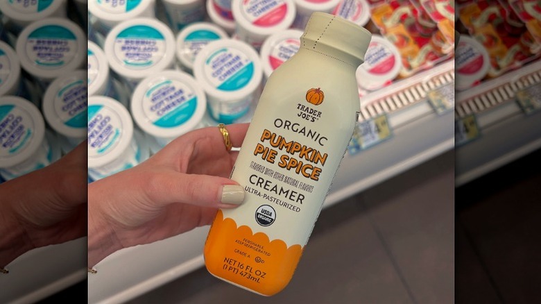 A woman holding a bottle of Trader Joe's new Organic Pumpkin Pie Spice Creamer