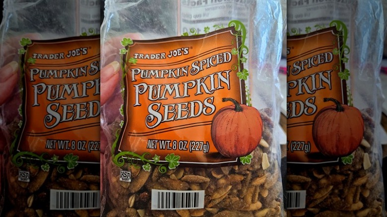 A hand holding a bag of Trader Joe's Pumpkin Spiced Pumpkin Seeds