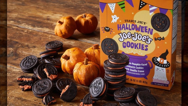 A pile of chocolate Trader Joe's Halloween Joe-Joe's cookies next to a cookie box and artificial pumpkins