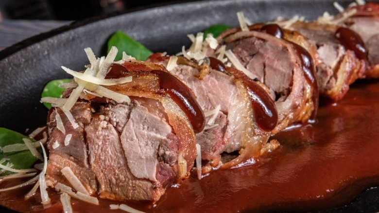 Sliced prime rib on a metal plate with sauce and garnish