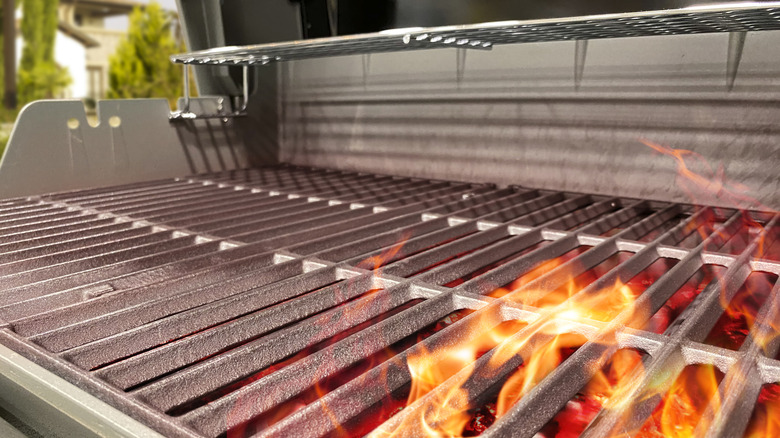 Stainless steel gas grill with flames shooting up between the grates