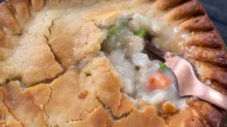 Close up of fork breaking the crust on a chicken pot pie