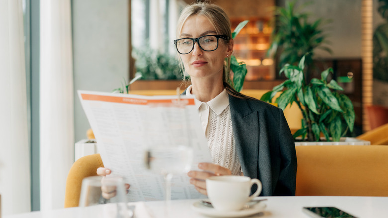 Woman in restaurant holding large menu