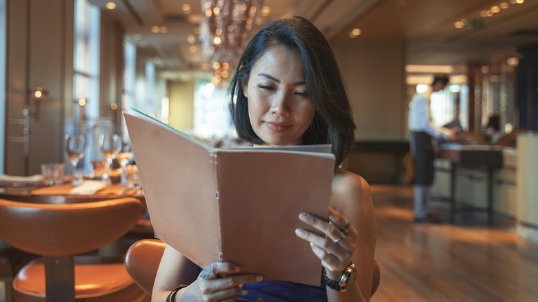 Woman reading menu at empty restaurant