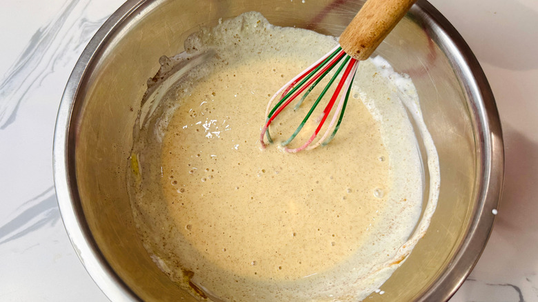 Wet pancake mixture in bowl with whisk