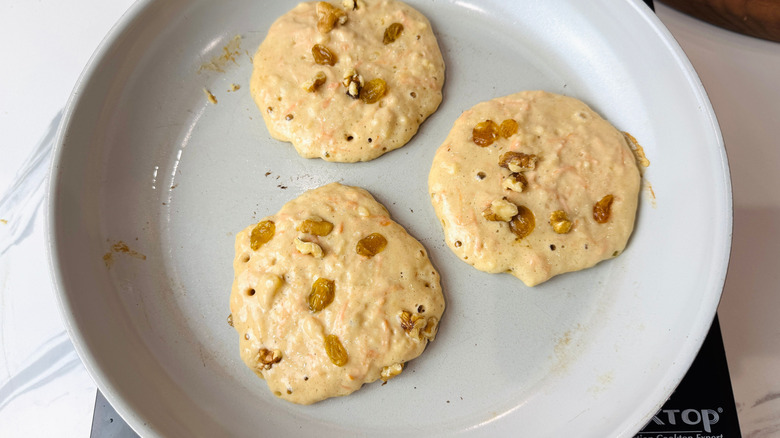Carrot cake pancakes in pan with raisins and walnuts