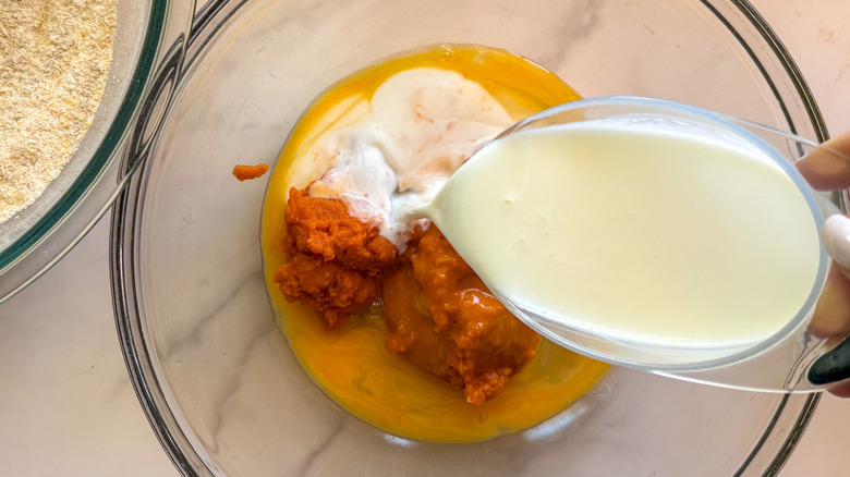 pouring milk into bowl with pumpkin puree