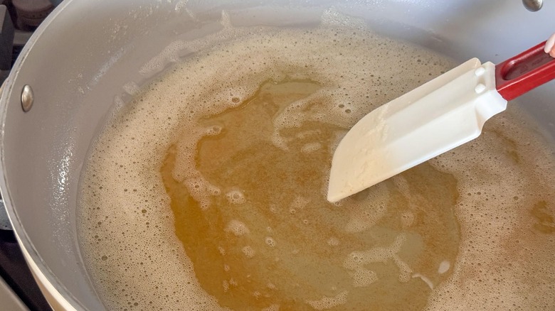 Spatula stirring brown butter in pan