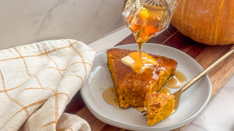 Pouring honey over pumpkin cornbread slice on plate