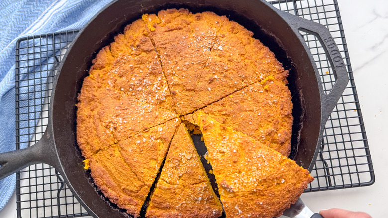 Removing slice of pumpkin cornbread from skillet