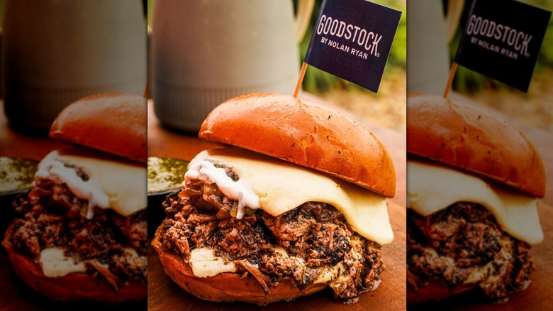 Brisket sandwich with melting cheese on a bun with a miniature blag toothpick flag that reads 