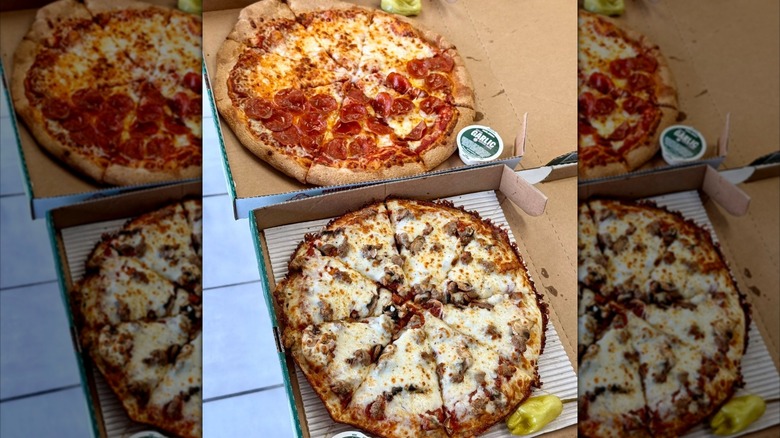 Two Papa John's Pan Pizza sit in a box with containers of dipping sauce nearby