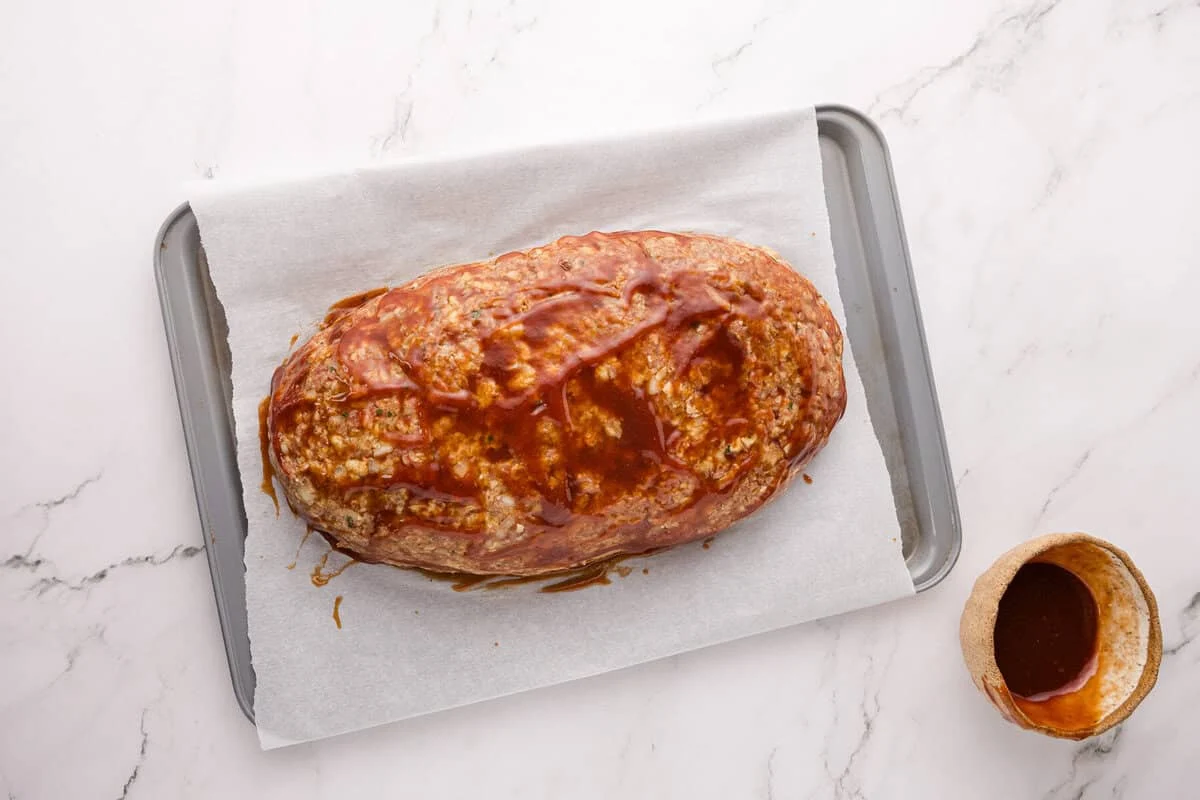 Unbaked meatloaf brushed with sweet and tangy ketchup glaze before baking