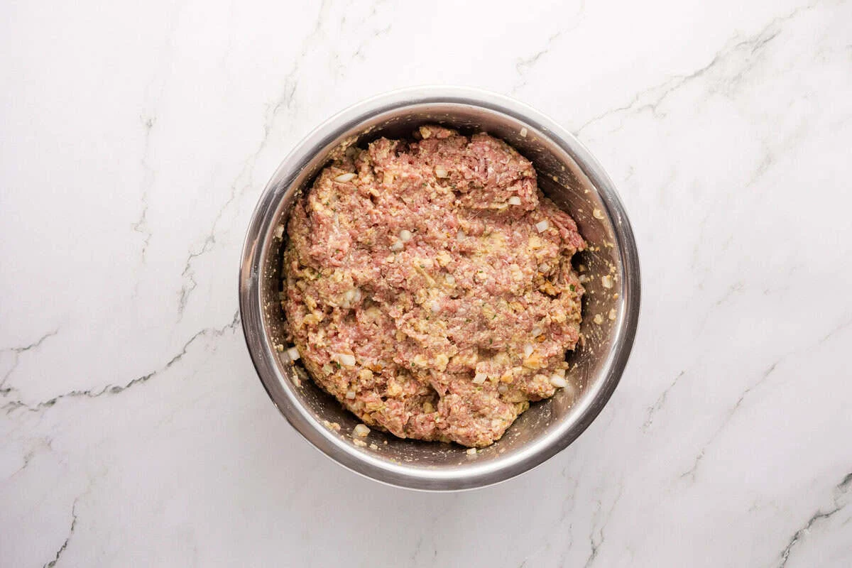 Ground beef and seasoned stuffing mixture combined in a bowl, ready to shape