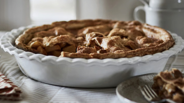 A pie is served in a round white pie plate with a ribbed trim.