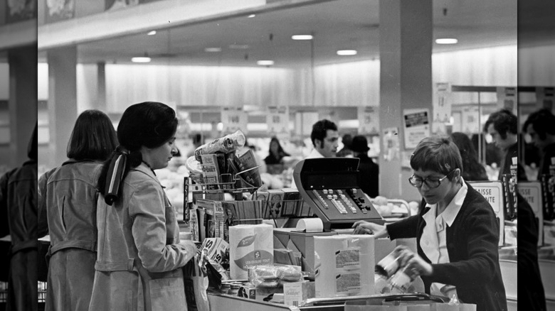 Cashier ringing up groceries at a 1970s checkout