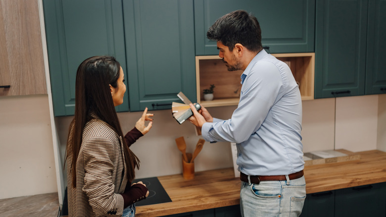 A couple standing in their kitchen and discussing cabinet design choices