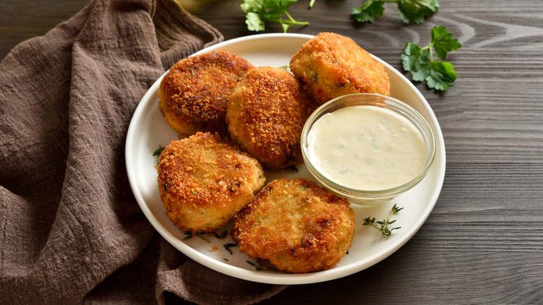 potato tuna patties on a plate, with a bowl or tartar sauce for dipping