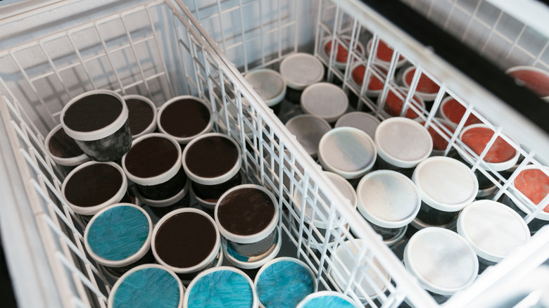 View of the top of different ice cream tubs inside a supermarket freezer
