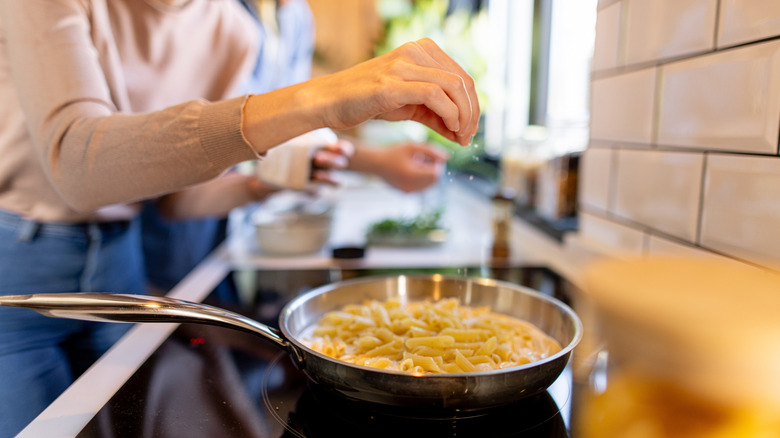 Woman cooking pasta on induction hob