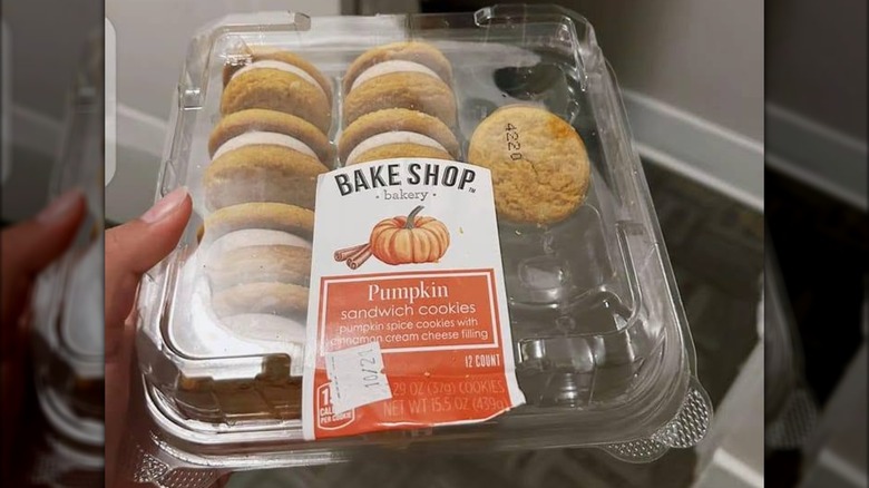 A woman holding a plastic package of Aldi Bake Shop Pumpkin Sandwich Cookies