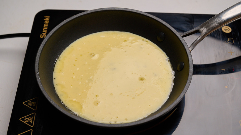 Raw omelet layer cooking in skillet