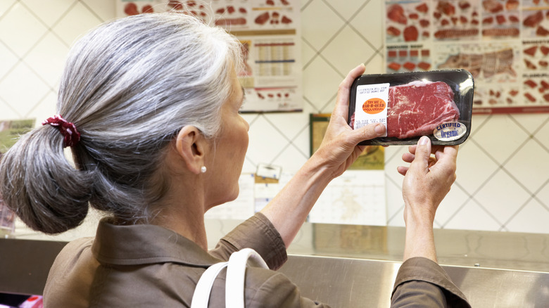 woman checking meat label in grocery store