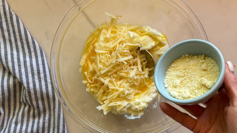 hand adding cheese to bowl