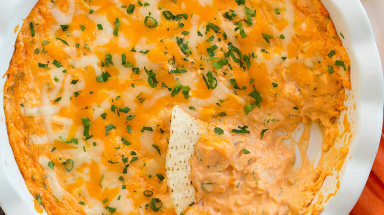 A bowl of Buffalo chicken dip with a tortilla chip sticking into it