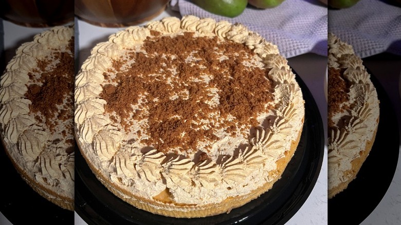 Whole Costco pumpkin cheesecake with whipped topping and graham cracker crumbs